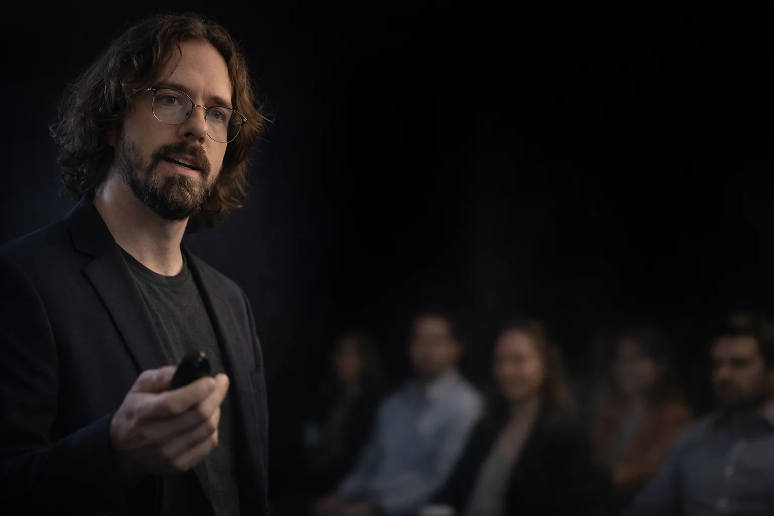 Erik Cadieux en présentation sur scène, confiant, auditoire à l'écoute